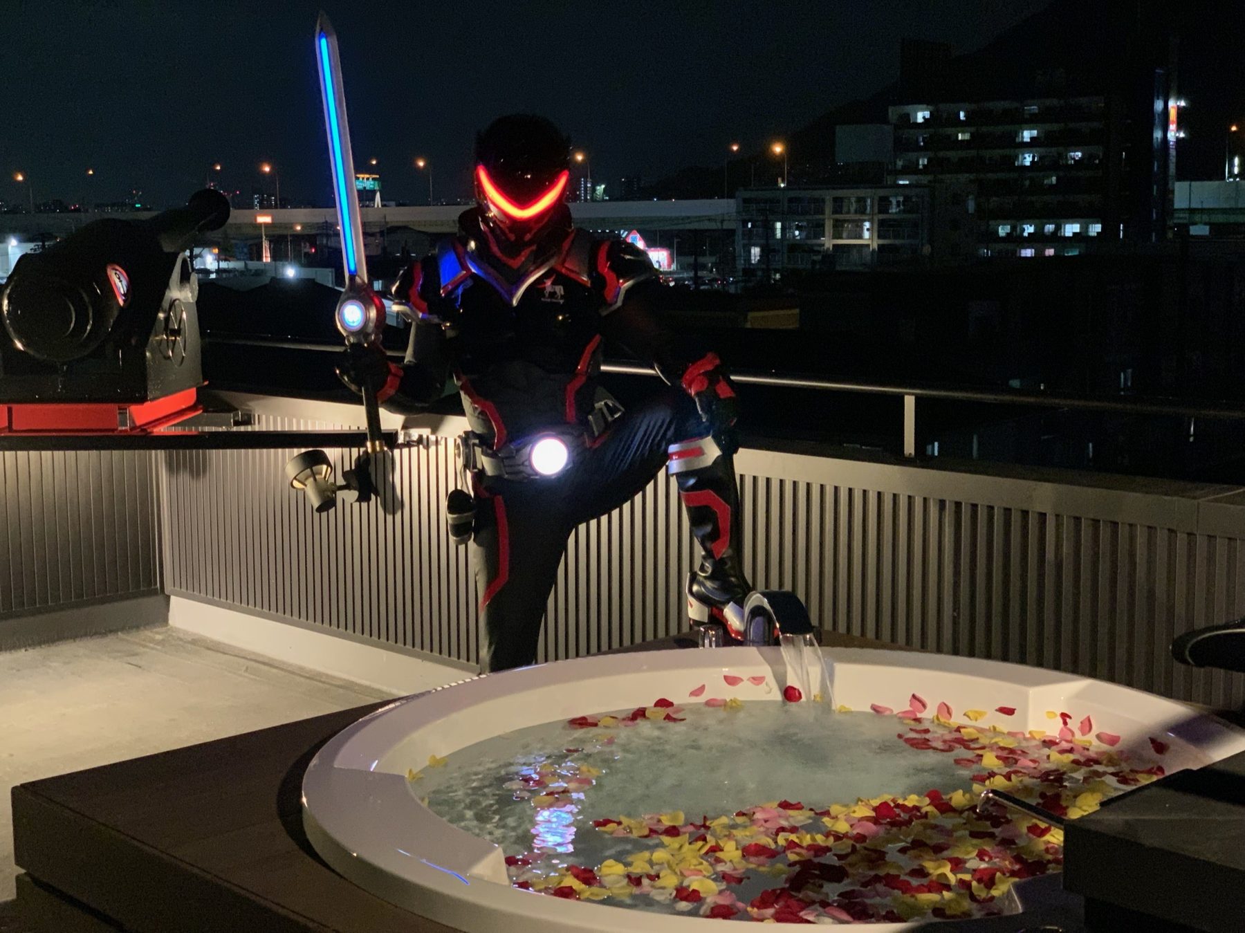 夜の屋上。花びらのジャグジーの縁に立つクロフネマンと、クロフネ砲