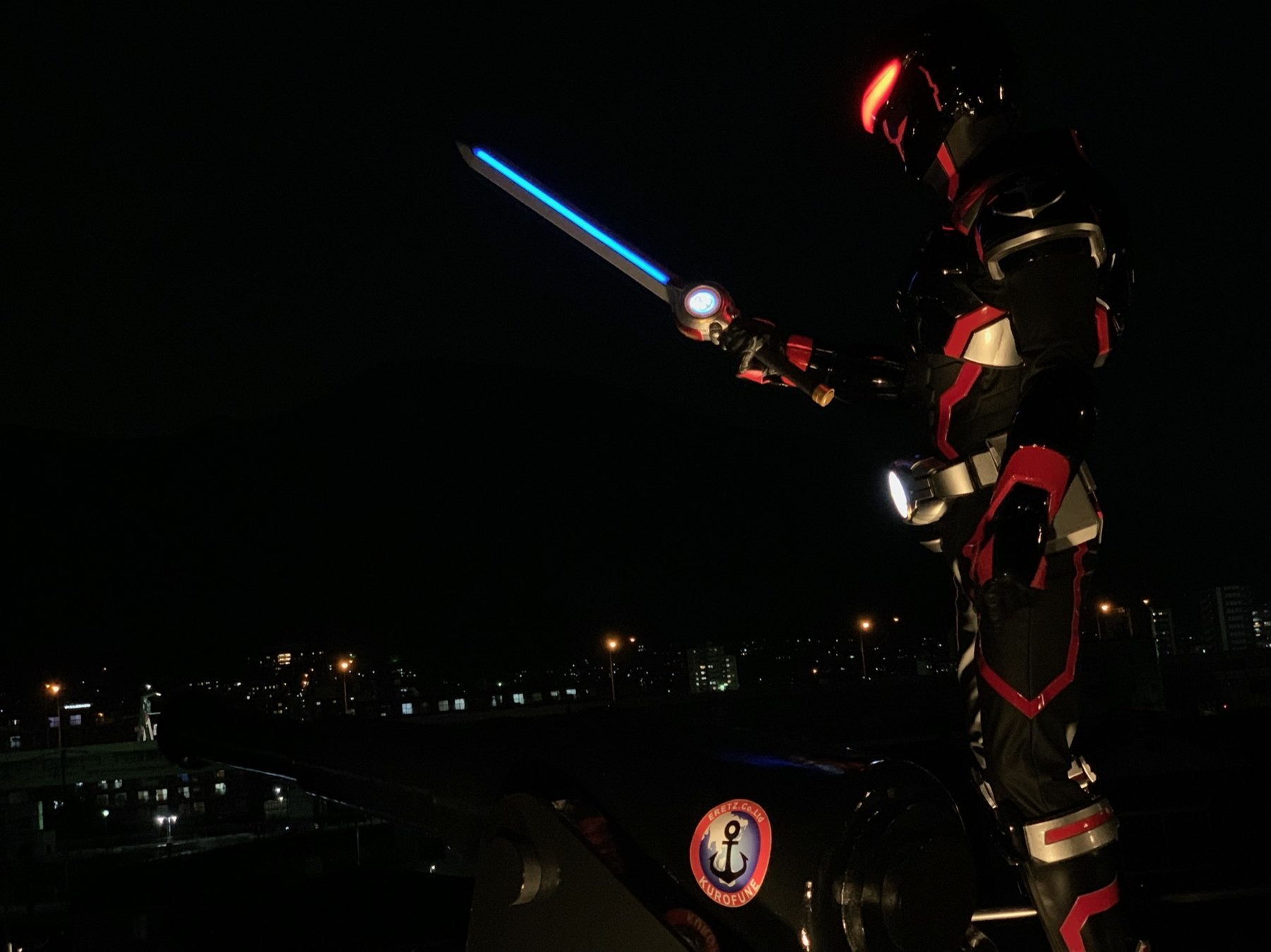 夜の屋上で、光る剣を構えるクロフネマン